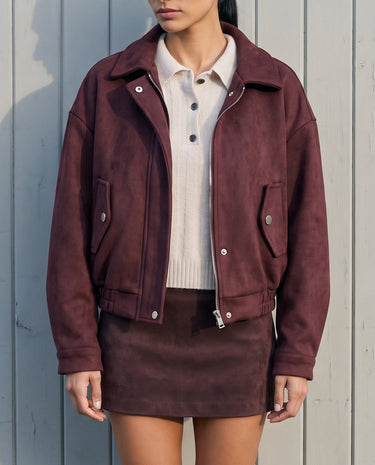 Model wearing the burgundy suede-look bomber jacket open over a cream polo top and matching mini skirt, front view
