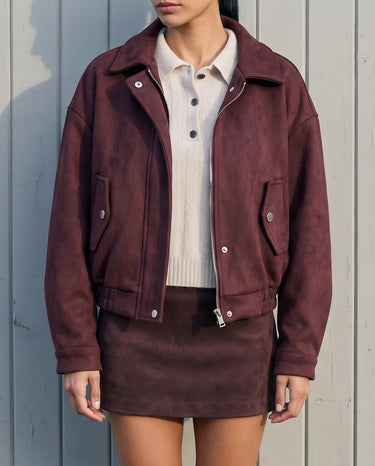 Model wearing the burgundy suede-look bomber jacket open over a cream polo top and matching mini skirt, front view