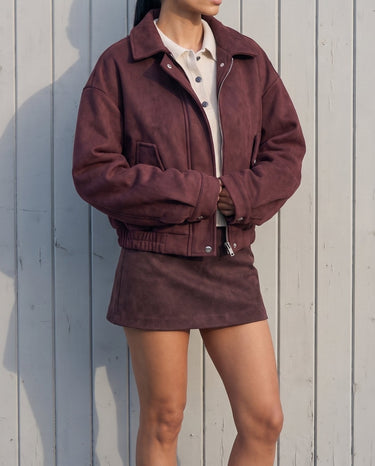 Model in the burgundy suede-look bomber jacket, full-length front view against a white wall