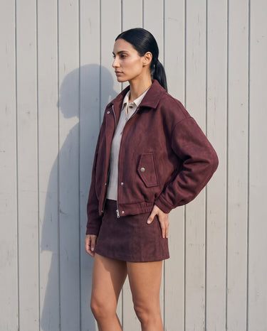 Three-quarter view of the burgundy suede-look bomber jacket showing the dropped shoulder and cuffed sleeves