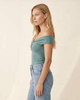 Side profile of the green off-shoulder top showing the fitted body – Moriel Heritage