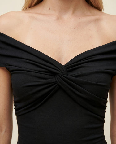 Close-up of the black top's twisted bust detail and off-shoulder neckline – Moriel Heritage