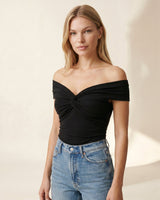 Model wearing the black off-shoulder twist-front top with high-waist jeans – Moriel Heritage