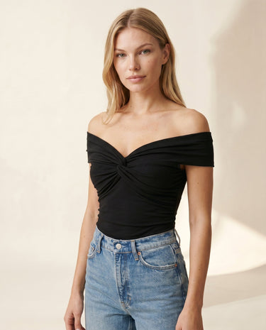 Model wearing the black off-shoulder twist-front top with high-waist jeans – Moriel Heritage
