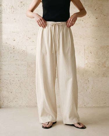 Cream wide-fit pants on model, hands resting at waist – Moriel Heritage