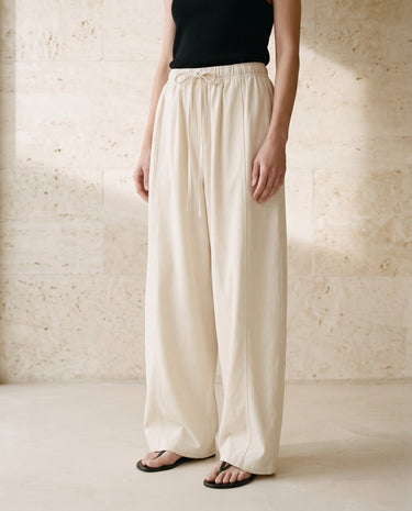 Cream wide-fit pants on model, soft pleat front view – Moriel Heritage