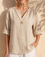 The Aire Relaxed Shirt in beige — relaxed V-neck shirt, front view on model