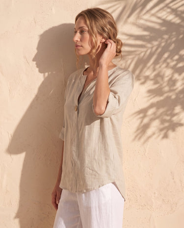 The Aire Relaxed Shirt in beige — relaxed V-neck shirt, side view on model