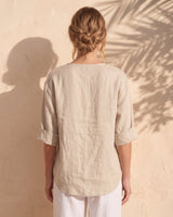 The Aire Relaxed Shirt in beige — relaxed V-neck shirt, back view on model