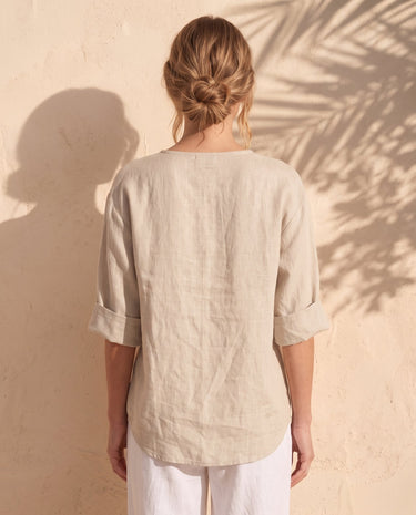The Aire Relaxed Shirt in beige — relaxed V-neck shirt, back view on model