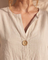 The Aire Relaxed Shirt in beige — close-up of V-neck and wood button detail