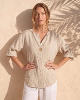 The Aire Relaxed Shirt in beige — relaxed V-neck shirt, front view on model