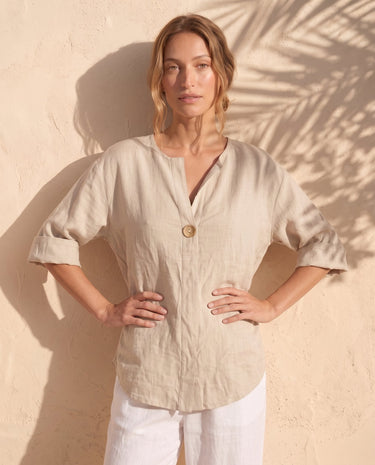 The Aire Relaxed Shirt in beige — relaxed V-neck shirt, front view on model