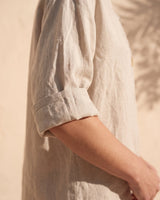 The Aire Relaxed Shirt in beige — close-up of rolled sleeve and linen texture
