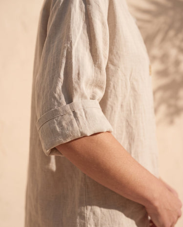 The Aire Relaxed Shirt in beige — close-up of rolled sleeve and linen texture