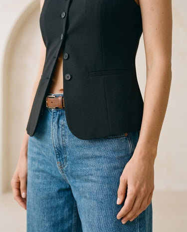 The Alicia vest in black — close-up of the open front worn over jeans on model