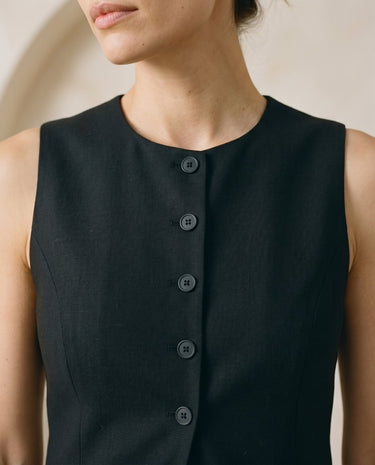 The Alicia vest in black — close-up of the neckline and button front