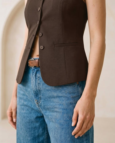 The Alicia vest in brown — close-up of the welt pocket worn over jeans on model