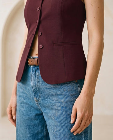The Alicia vest in burgundy — close-up of the welt pocket worn over jeans on model