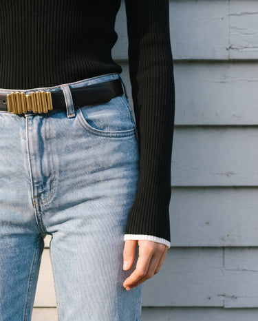 Close-up of the knit top's contrast cuff trim and fitted waist over jeans – Moriel Heritage