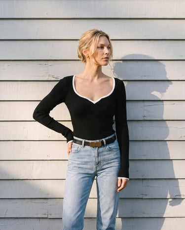 Model with hand on hip wearing the black ribbed knit top, angled front view – Moriel Heritage