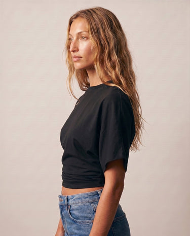 Side view of the black ruched-side tee showing the gathered seam – Moriel Heritage