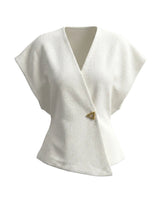 The Asymmetrical Vest in white — textured sleeveless vest with V wrap front and single button, product flat-lay
