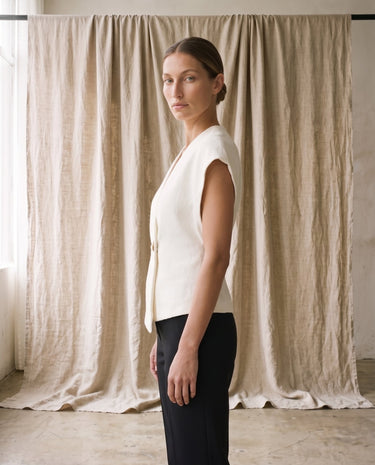 The Asymmetrical Vest in white — textured sleeveless vest, side view on model