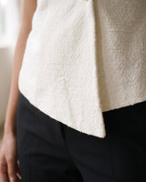 The Asymmetrical Vest in white — close-up of the asymmetric hem detail