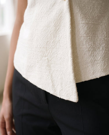 The Asymmetrical Vest in white — close-up of the asymmetric hem detail