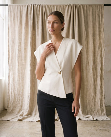 The Asymmetrical Vest in white — textured sleeveless vest, front three-quarter view on model