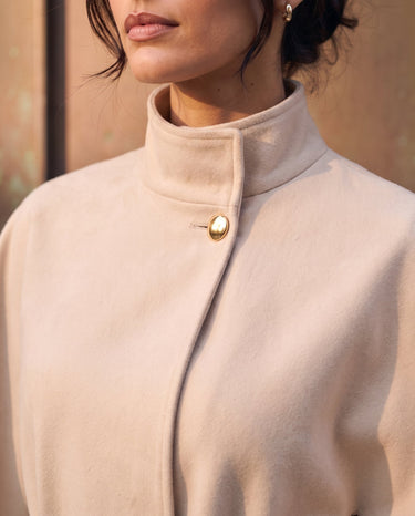 The Aurelia Shawl in beige — close-up of the stand collar and gold button