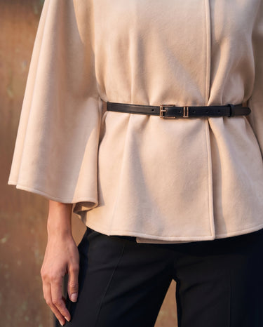 The Aurelia Shawl in beige — close-up of the belted waist and draped cape sleeve