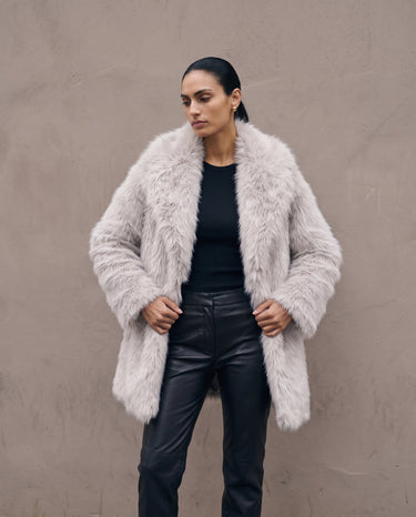 Model standing in the light gray Ballerina Faux Fur Coat, front view showing the thigh-length cut