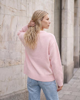 The Blush Sweater in pink — back three-quarter view on model