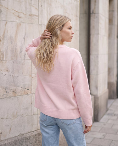 The Blush Sweater in pink — back three-quarter view on model