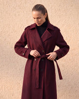 The Burgundy Celine Coat in burgundy — front view on model tying the belt