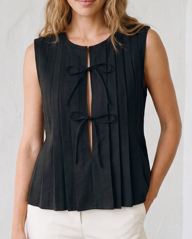 The Cala Cotton Linen Tie Top in black — sleeveless pleated tie-front top, front view on model