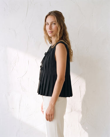 The Cala Cotton Linen Tie Top in black — pleated sleeveless top, side view on model