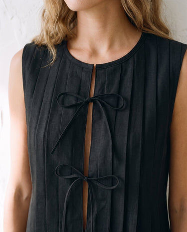 The Cala Cotton Linen Tie Top in black — close-up of front bow ties and pleated placket