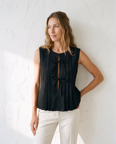 The Cala Cotton Linen Tie Top in black — pleated tie-front top, three-quarter view on model