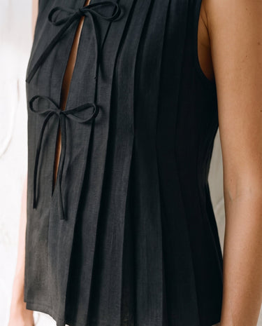 The Cala Cotton Linen Tie Top in black — close-up of bow-tie placket and pleating