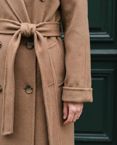 The Calvera double-breasted wool coat in khaki — close-up of the belted waist and buttoned cuff