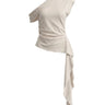 The Camellia Ruffle Top in beige — one-shoulder draped top with cascading ruffle panel, product flat-lay