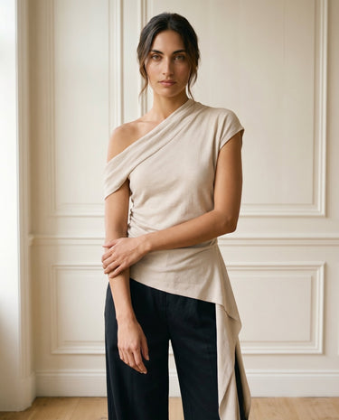 The Camellia Ruffle Top in beige — asymmetric one-shoulder draped top, three-quarter view on model