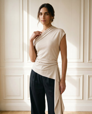 The Camellia Ruffle Top in beige — one-shoulder draped top, front view with movement on model