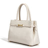 The Camille Handbag in ivory, three-quarter studio view showing the structured shape and rolled top handles