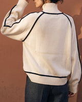 Model wearing cream high-neck knit sweater, back view showing raglan piping – Moriel Heritage