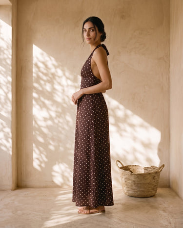 The Capri Polka Dot Dress in brown — polka-dot halter maxi dress, side view on model