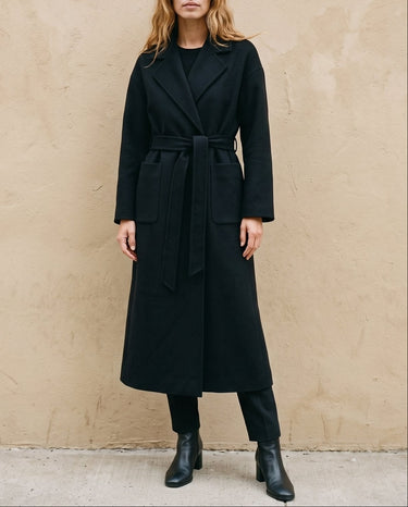 The Caroline Tie Waist Coat in black — longline belted coat, front view on model